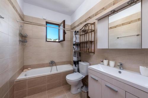 a bathroom with a toilet and a tub and a sink at Villa Kiotari by Villa Plus in Kiotari