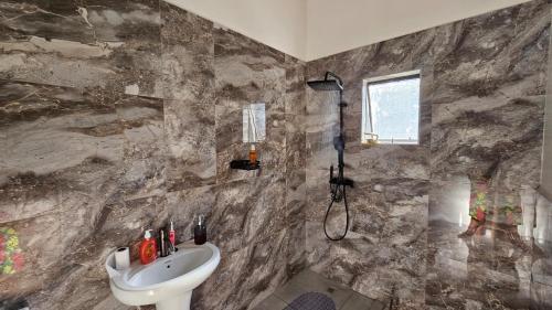 a stone bathroom with a sink and a shower at Jacaranda Escape in Pretoria