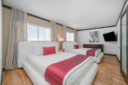 a bedroom with two white beds and a television at Metropole Suites South Beach in Miami Beach