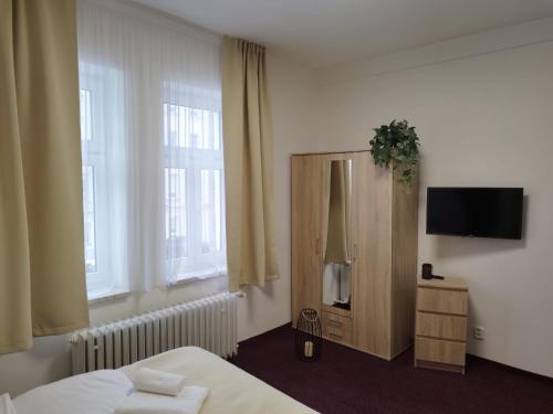 a bedroom with a bed and a tv and windows at Hotel Incognito in Jáchymov