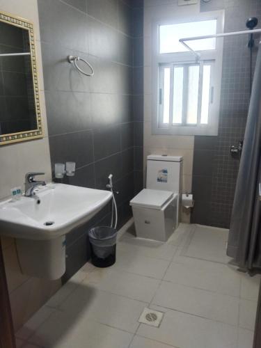a bathroom with a sink and a toilet and a window at Marine Beach Apartment in Seef