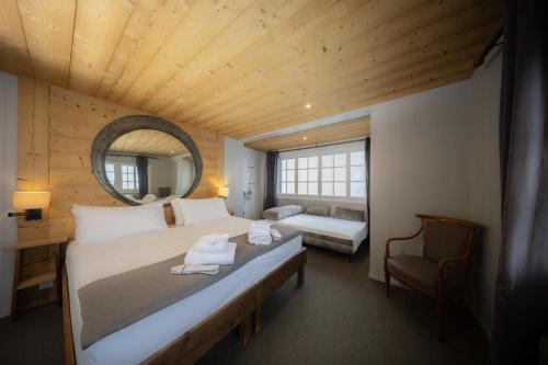 ein Schlafzimmer mit einem großen Bett mit Spiegel und Stuhl in der Unterkunft Le Coucou Hotel Restaurant & Lounge-Bar in Montreux