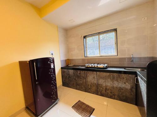 a kitchen with a black refrigerator and a window at Aroma Residency 2bhk villa & delux rooms in Mahabaleshwar