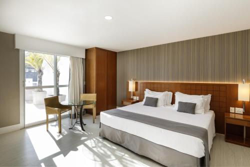 a bedroom with a bed and a desk and a table at Promenade Palladium Leblon in Rio de Janeiro