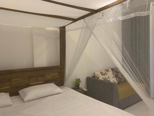 a bedroom with a bed and a chair and a window at Menuks villa in Habaraduwa Central