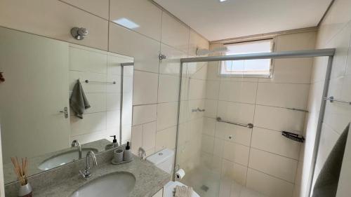a bathroom with a sink and a shower with a mirror at Edifício Aquarius in Ribeirão Preto