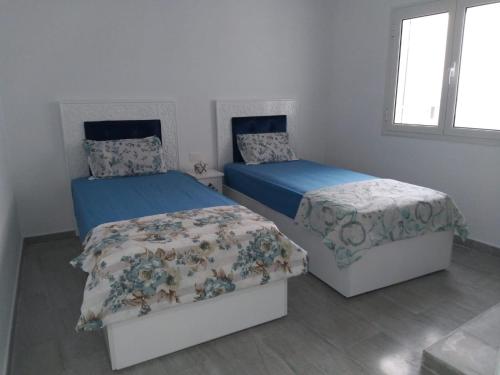 a bedroom with two beds with blue sheets at Dar Leïla in Harqalah