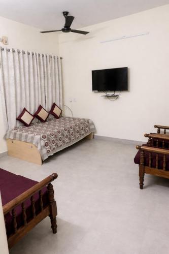 a living room with a bed and a flat screen tv at Zest Homes Nugambakkam in Chennai