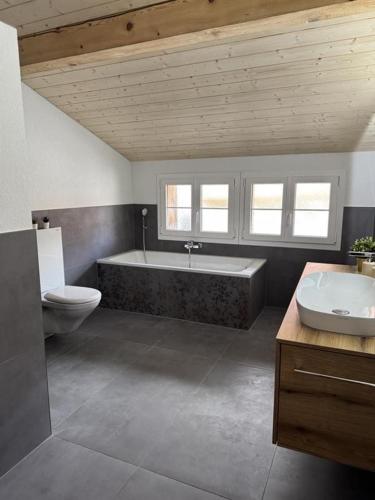 a bathroom with a tub and a toilet and a sink at Chalet Gadmer Herz in Gadmen