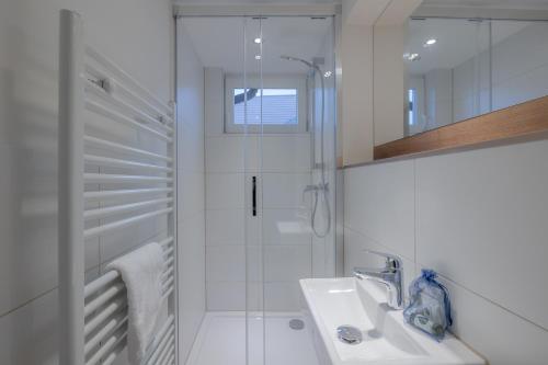 a white bathroom with a shower and a sink at Ankerplatz Sylt in Sylt
