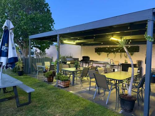 an outdoor patio with tables and chairs and an umbrella at Lakeside Motel Waterfront in Lakes Entrance