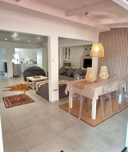 a dining room and living room with a table and a couch at Die Boomhuis. Pearly Beach in Pearly Beach