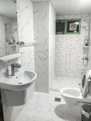 a white bathroom with a sink and a toilet at Everest Stay in Abu Dhabi