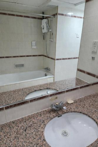 a bathroom with a sink and a tub and a mirror at 1BR Seaview Condo with Balcony at Riviera Bay Resort, Melaka in Malacca