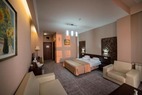 a hotel room with a bed and two chairs at Hotel Secret Garden in Baia-Sprie