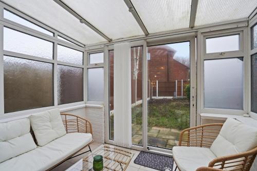 a screened in porch with white furniture and windows at Modern Refurbished 2 Bed House Ideal for Business & Families in Newton Road Station