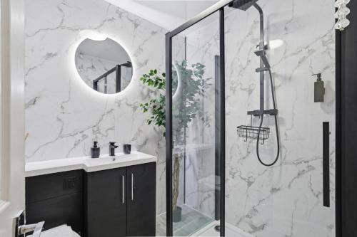 a bathroom with a shower and a sink and a mirror at Modern Refurbished 2 Bed House Ideal for Business & Families in Newton Road Station