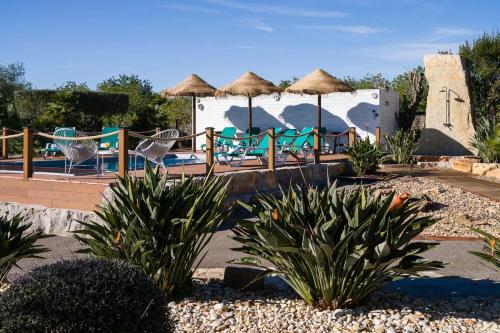 a resort with a pool with chairs and umbrellas at VILLA CARACOL with Heated Pool & Mini-Golf in Luz de Tavira