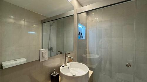 a white bathroom with a sink and a shower at En el Corazón de Rosario in Rosario