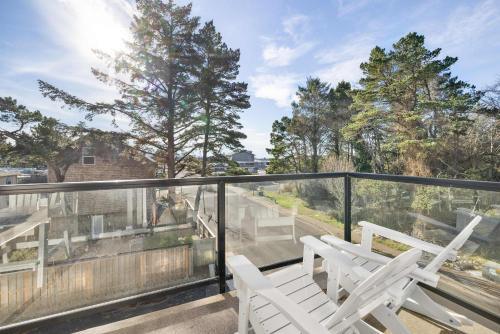 two white chairs on a balcony with trees at Bay View Loft in Lincoln City