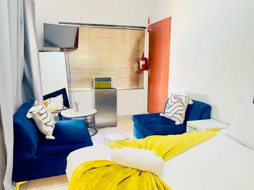 a bedroom with a bed and two blue chairs at Genza Guesthouse in Pretoria in Pretoria