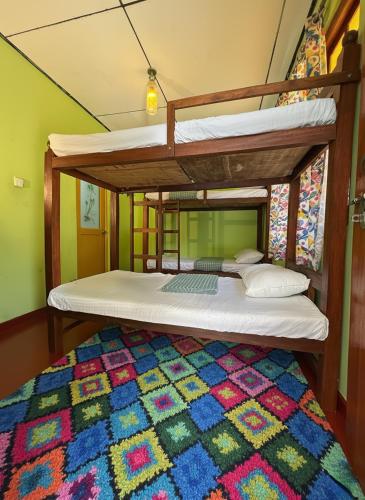 two bunk beds in a room with a colorful rug at The Bunker Hostel Ella in Ella