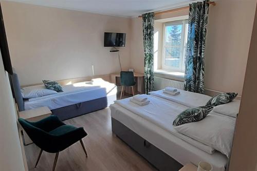 a room with two beds and a chair and a window at Dom Litewski in Sejny