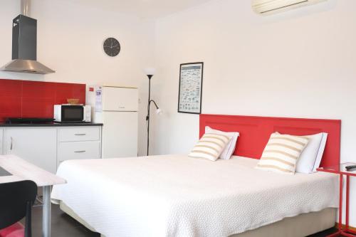 a bedroom with a white bed and a red headboard at Faial Marina Apartments 1 in Horta