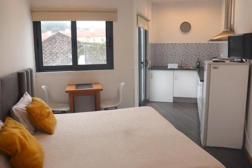 a room with a bed and a kitchen with a refrigerator at Faial Marina Apartments 1 in Horta