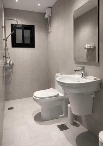 a bathroom with a white toilet and a sink at Riwaq suite in Jeddah