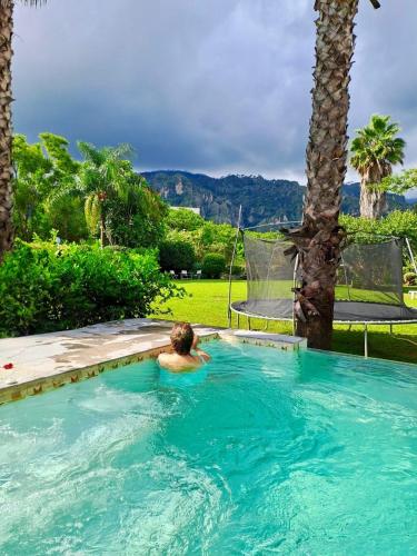 a man in a swimming pool with a palm tree at Calli Hotel Tepoztlán in Tepoztlán