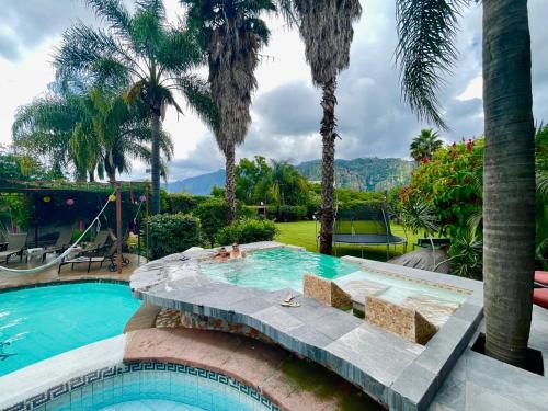 a swimming pool with palm trees in a resort at Calli Hotel Tepoztlán in Tepoztlán