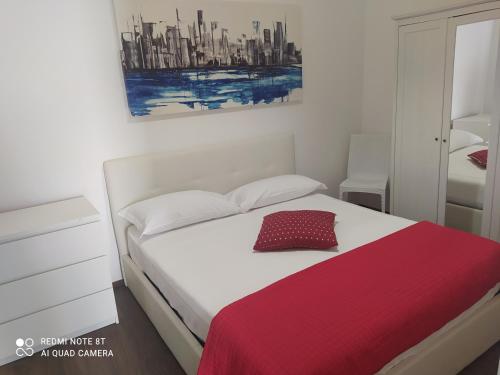 a bedroom with a white bed with a red blanket at Le case di Roberto in Gioia del Colle
