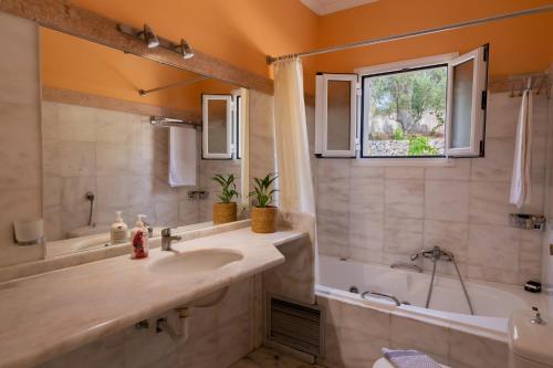 a bathroom with a sink and a tub and a window at Villa Nefeli Breeze in Dassia