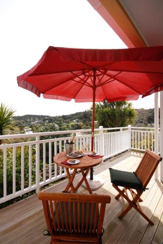 a wooden deck with a table and a red umbrella at Bellrock Lodge in Russell