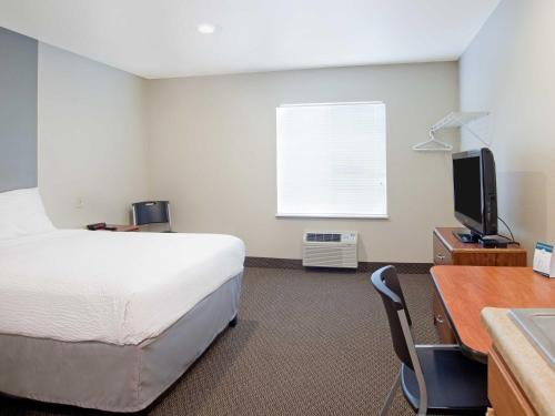
a hotel room with a bed and a television at WoodSpring Suites Dickinson in Dickinson
