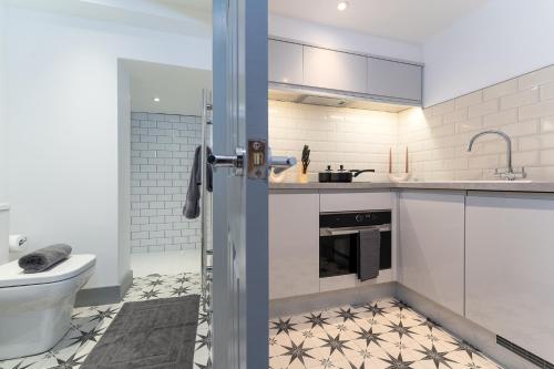 a white kitchen with a sink and a toilet at The Madison - Premium Self Check-In Studios & Apartments in Southampton