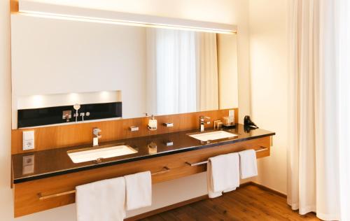 a bathroom with two sinks and a large mirror at B&O Parkhotel in Bad Aibling