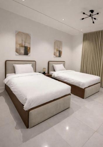 two beds in a bedroom with white walls at Riwaq suite in Jeddah