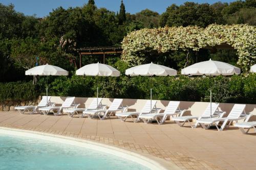 a group of white chairs and umbrellas next to a pool at Les Hauts de Santa Giulia in Porto-Vecchio