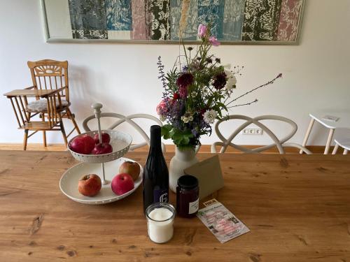 a table with a bottle of wine and a vase with fruit at Ferienwohnung Anstois in Kall