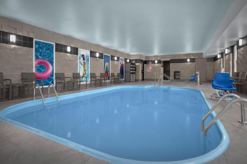a large swimming pool in a building with blue chairs at Holiday Inn Express Fargo - West Acres by IHG in Fargo