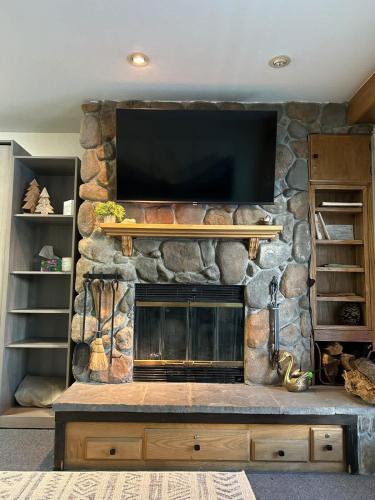 a stone fireplace with a flat screen tv on a wall at The Meadows- Charming 1BD2BA Ski Condo in Kirkwood
