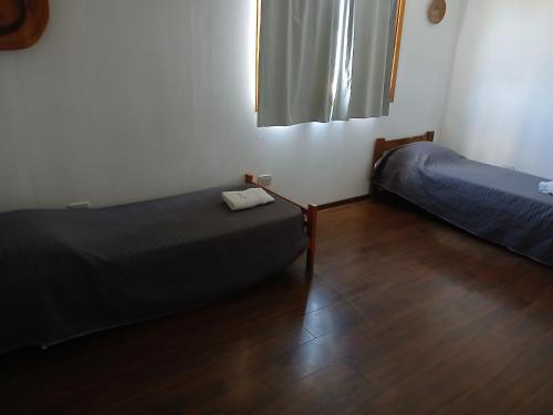 a small room with two beds and a wooden floor at Depto Castillo in El Bolsón