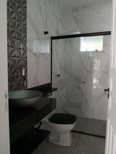 a bathroom with a toilet and a sink and a shower at Casa central com piscina! in Guaratuba
