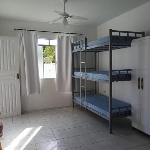 a room with three bunk beds and a window at Casa central com piscina! in Guaratuba