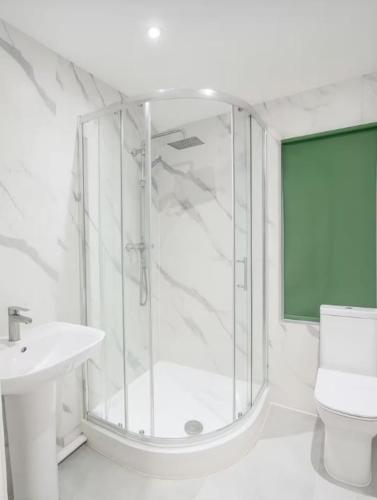 a white bathroom with a shower and a sink at Lincoln Manor 5BR in Peterborough