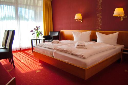 a bedroom with a large bed with two chairs at Hotel Goldener Fasan in Oranienbaum-Wörlitz