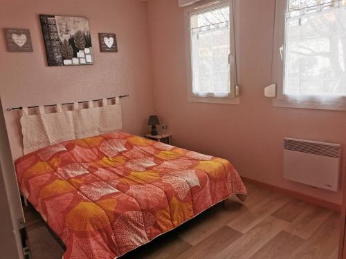 a bedroom with a bed with a colorful comforter and two windows at Gîtes Marschall Jean-Pierre in Beblenheim