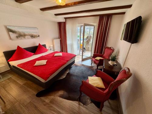 a bedroom with a red bed and two chairs at Haus Edeltrud - Ferienwohnung Moselufer in Bernkastel-Kues